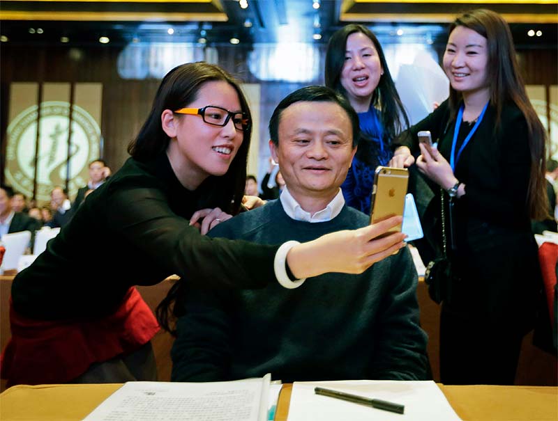 Alibaba founder and executive chairman Jack Ma is this year’s biggest financial gainer as the billionaire entrepreneur’s fortune has swelled by a whopping USD 18.5 billion this year to USD 29.2 billion, a report says. According to private wealth consultancy, Wealth-X, the former English teacher-turned billionaire entrepreneur is the biggest gainer of this year as his fortune increased 173 per cent, largely due to Alibaba’s blockbuster IPO in September and the subsequent strong performance of the company’s stock.<br>(In pic) A female delegate takes a 'selfie' with Alibaba Group Executive Chairman Jack Ma as he arrives for the Fifth Conference of Zhejiang Chamber of Commerce in Beijing. (Image: Reuters)