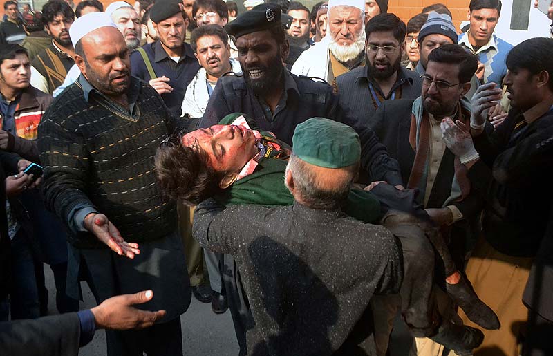 Hospital security guards carry a student injured in the shootout at a school attacked by Taliban gunmen in Peshawar, Pakistan. AP