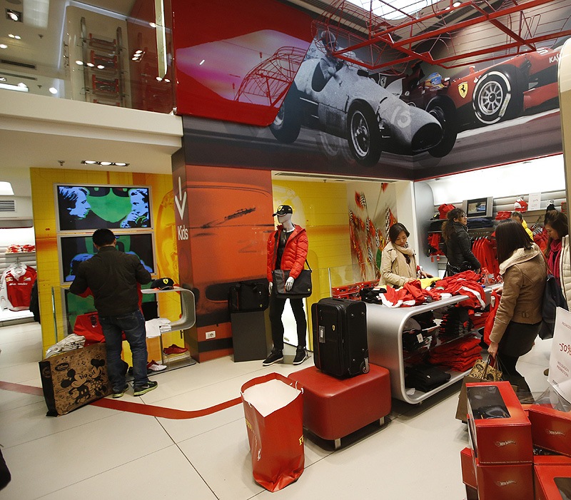 People look at clothing in a Ferrari Store in Milan. Analysts say that could mean refining its line of merchandise or creating a chain of exclusive clubs and hotels catering to Ferrari owners and the wealthy. (AP)