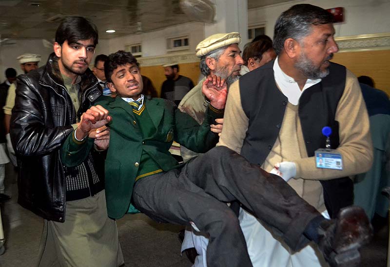 Pakistani volunteers carry a student injured in the shootout at a school attacked by Taliban gunmen. AP