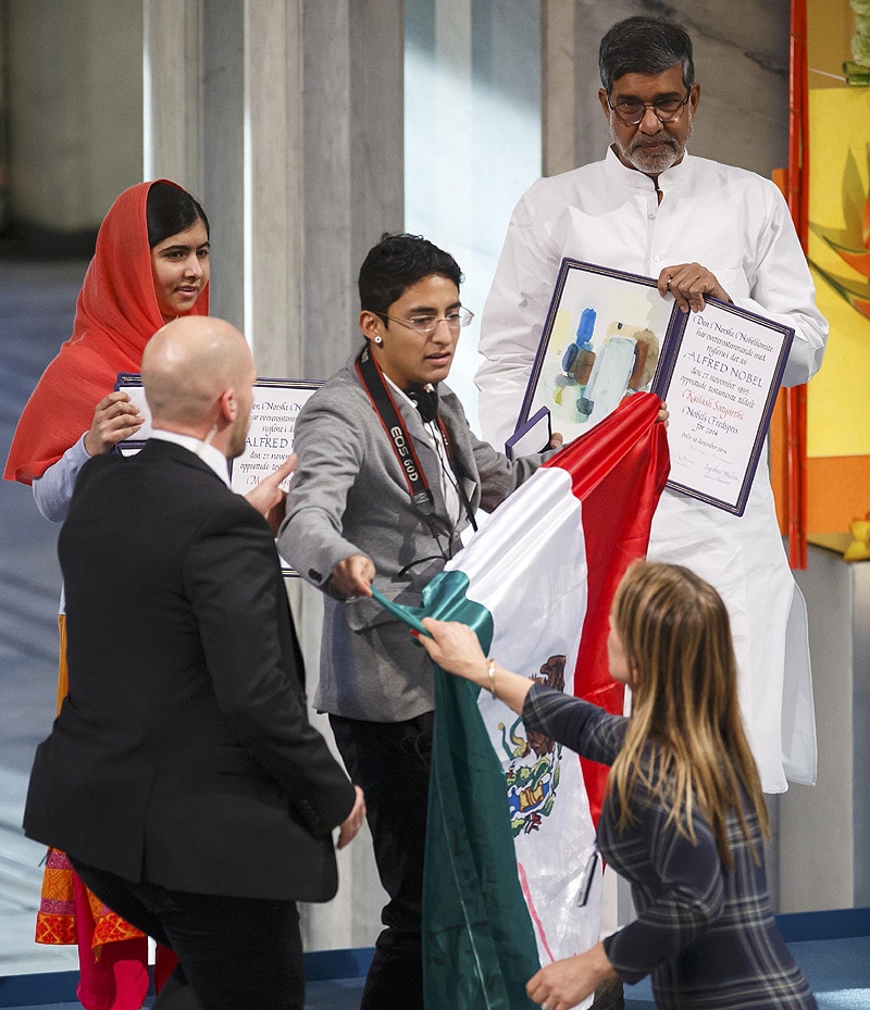Nobel Peace Prize laureates Malala Yousafzai (back L) and Kailash Satyarthi (R) pose with their medals as a security officers take away a protester with the flag of Mexico during the Nobel Peace Prize awards ceremony. (Reuters)