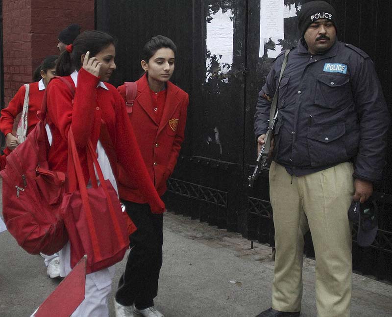 A Pakistani police officer stands guard as students arriving to attend their school in Lahore, Pakistan. (AP/PTI)