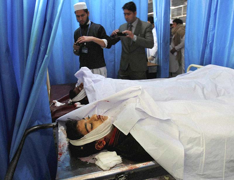 Pakistanis use their mobile phones to take photographs of students who died in a Taliban attack on their school, at a local hospital in Peshawar. (AP)