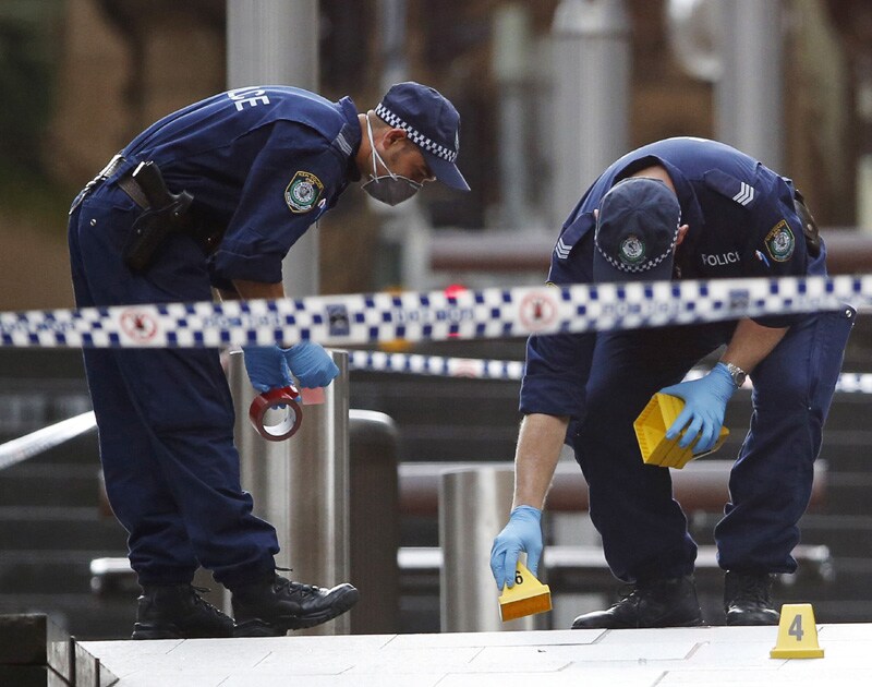 New South Wales police officers wear protective masks as they place marker cones over potential evidence in their investigation into the cafe siege, Sydney, Australia.