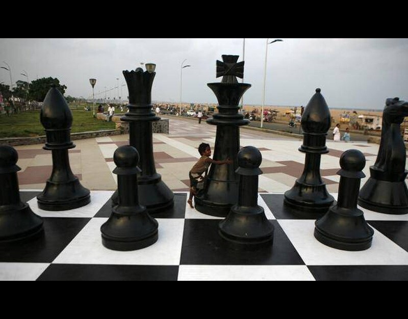 An Indian child plays around a huge chessboard model erected to mark the World Chess Championship at the Marina beach on the Bay of Bengal coast in Chennai, India, on Thursday. (AP)