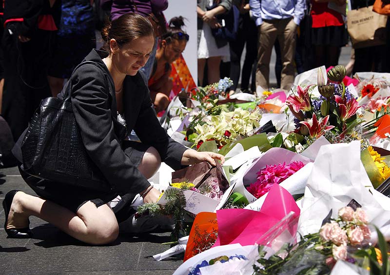 A woman places a floral tribute amongst thousands of others near the cafe in central Sydney where hostages were held for over 16-hours. Reuters