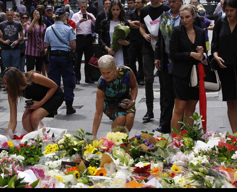 Women offer flowers at a makeshift memorial in Sydney, Australia on Dec. 16, 2014 near where three people died in a siege. An Iranian-born gunman took 17 people hostage at a central city cafe Monday before police stormed the cafe early Tuesday. The gunman and two hostages were killed.