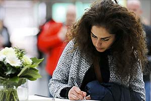 A woman writes in a book of condolences in Duesseldorf airport March 25, 2015. French investigators on Wednesday searched for the reason why a German Airbus ploughed into an Alpine mountainside, killing all 150 on board including 16 teenagers returning from a school trip to Spain. Helicopters flew over the site where the A320 operated by Lufthansa's Germanwings budget airline disintegrated after it went down in a remote area of ravines en route to Duesseldorf from Barcelona. REUTERS