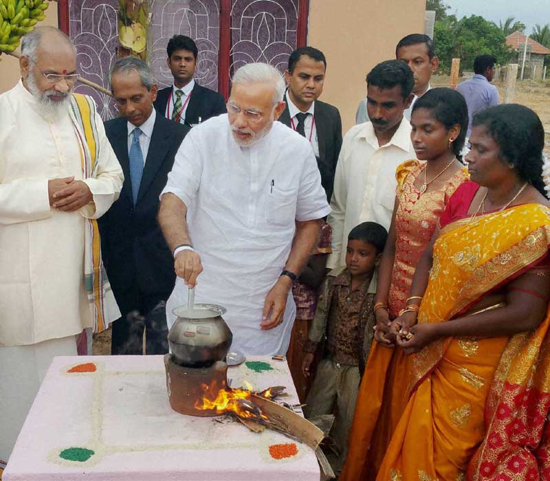 Prime Minister Narendra Modi helping a family in house warming before it moved into a home of the Indian Housing Project in Jaffna in Sri Lanka on Saturday. PTI