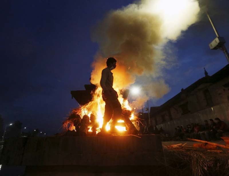 A man walks next to the burning pyre of a family member, who died in Saturday's earthquake, during the cremation along a river in Kathmandu, Nepal April 28, 2015. (Reuters)