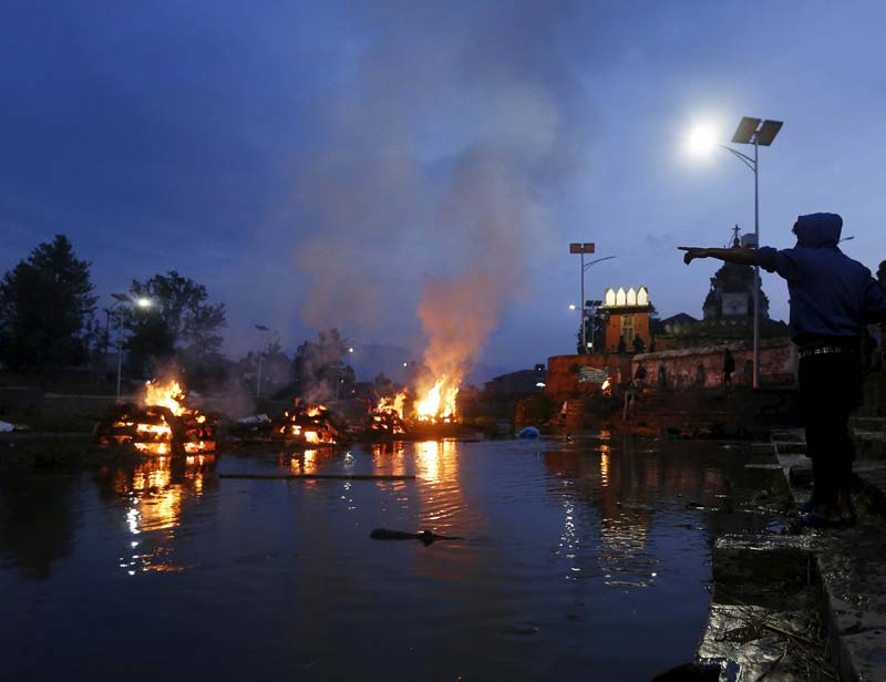 A boy points towards the burning pyres of his family members, who died in Saturday's earthquake, during the cremation along a river in Kathmandu, Nepal April 28, 2015. (Reuters)