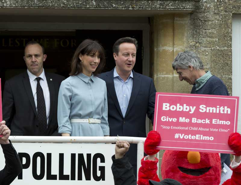 Britain's Prime Minister and Conservative Party leader David Cameron and his wife Samantha leave a voting station in Spelsbury, England, as protesters demonstrate outside after they voted in the general election, Thursday, May 7, 2015. Polls have opened in Britain's national election, a contest that is expected to produce an ambiguous result, a period of frantic political horse-trading and a bout of national soul-searching. (AP)