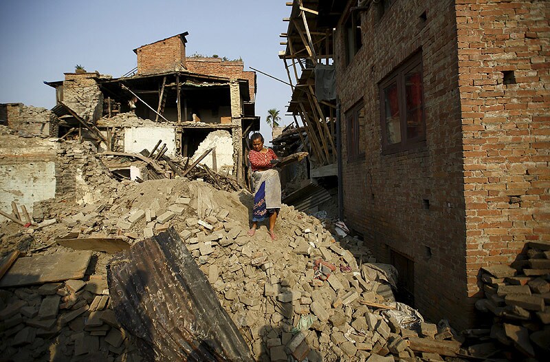 <b>Bihar places five districts on alert after Nepal landslide: </b> The Bihar government today sounded flood alert in five districts after a massive landslide, triggered by recent earthquakes, blocked the Kali Gandaki river at Benibazar in Myagdi district of Nepal, leading to accumulation of a huge volume of water there. "We have alerted East Champaran, West Champaran, Gopalganj, Siwan and Saran districts on the situation. Our department officials are also on alert. We have asked them to be prepared as a sudden breach in the Kali Gandaki river blockage may increase the water level," Water Resources Department (WRD) Secretary Dipak Kumar Singh said. Several hundred villages dot the low-lying riverine area of Gandak and they are the ones that face the immediate threat from the rising level of water. (Reuters) (25/05/2015) </br><br> (Image caption: Woman carrying blocks of wood recovered from her house walks along debris of collapsed houses, a month after the April 25 earthquake in Bhaktapur, Nepal.)