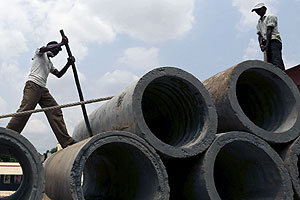 Labourers unload cement sewer pipes from a trailer truck along a roadside on the outskirts of Ahmedabad, India, June 9, 2015. REUTERS