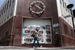 A woman walks in front of a closed down bank in the neighborhood of Rio Piedras in San Juan, Puerto Rico on Monday, June 29, 2015. (Photo: AP)