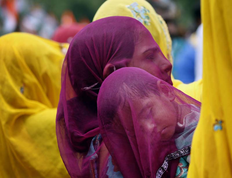 An Indian woman covers a sleeping child with her veil as she carries him on her shoulder at Ajmer in India’s Rajasthan state. (Image & text courtesy: Associated Press)