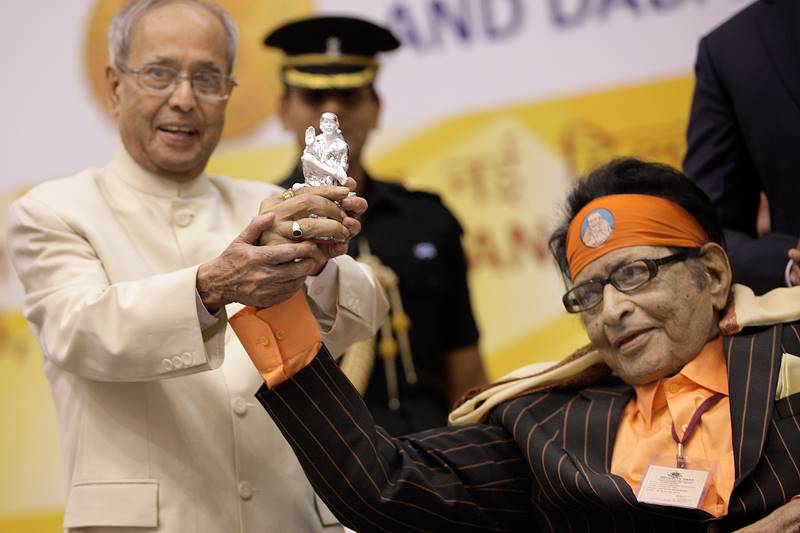 President Pranab Mukherjee presented the 63rd National Awards, including best actor trophy to Bollywood megastar Amitabh Bachchan, best actress to Kangana Ranaut and Dadasaheb Phalke award to Hindi film veteran Manoj Kumar. 78-year-old Kumar, best known for his patriotic films "Purab Aur Paschim", "Upkar" and "Kranti", became the 47th recipient of the award, the highest recognition in Indian cinema, which consists of a golden lotus, a cash prize of Rs 10 lakh and a shawl. The wheelchair-bound actor, who was sporting an orange bandana of Sai Baba, also presented the President with a crystal statue of the deity as he received the honour. (Photo: Neeraj Priyadarshi)