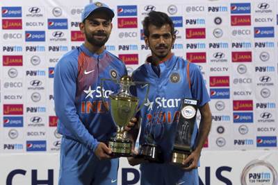 Indian cricket team captain Virat Kohli and teammate Yuzvendra Chahal pose with the winners and Man of the Series trophies after their win over England in their third Twenty20 international cricket match at Chinnaswamy Stadium in Bangalore. (AP)