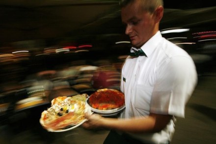 A waiter carries pizzas at the Ai Marmi restaurant in the Rome neighborhood of Trastevere May 11, 2007. REUTERS/Dario Pignatelli