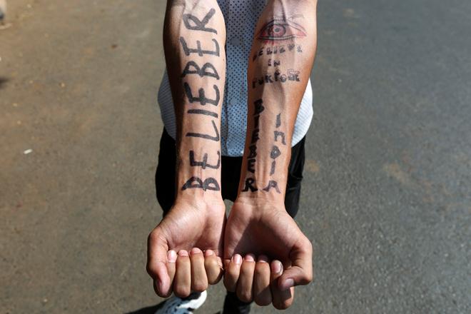 A fan of Canadian singer Justin Bieber shows his temporary tattoos as he waits for his arrival outside the airport in Mumbai. (Reuters)