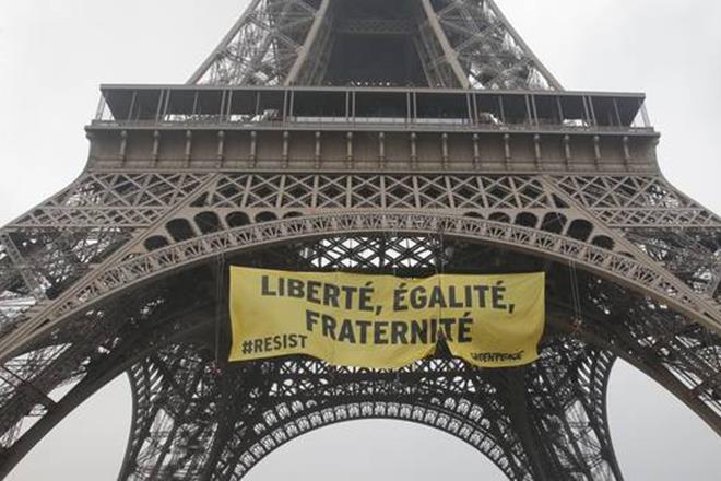 Greenpeace activists display a banner at the Eiffel tower that reads,’liberty, equality, fraternity’ in Paris on Friday. (AP) Greenpeace activists display a banner at the Eiffel tower that reads,’liberty, equality, fraternity’ in Paris on Friday. (AP)