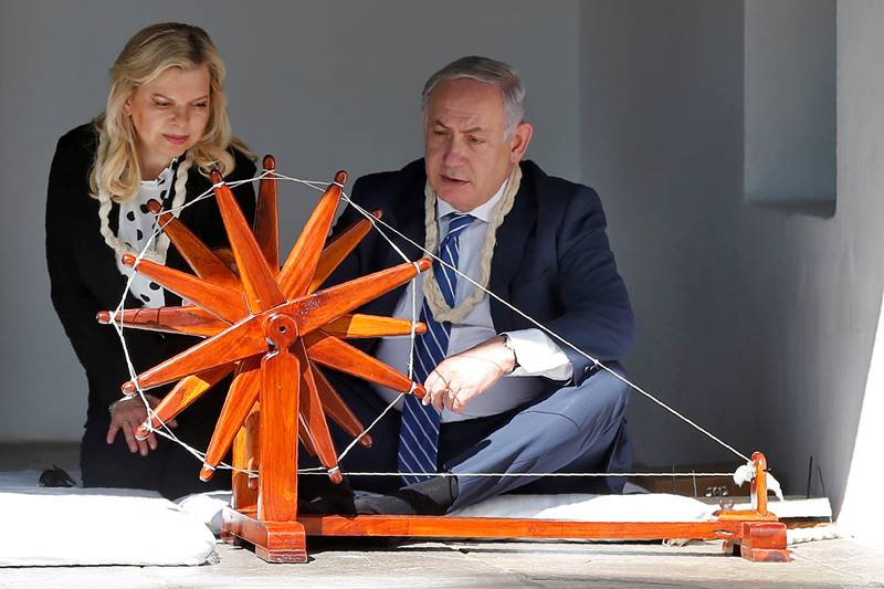 Israeli Prime Minister Benjamin Netanyahu spins cotton on a wheel as his wife Sara looks on during their visit to Sabarmati Ashram in Ahmedabad. (Image: Reuters)