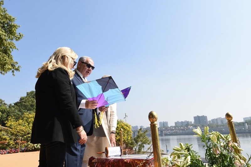 Netanyahu's wife, Sara is seen curiously looking at the skies and helping her husband fly the kite. (Source: PIB)