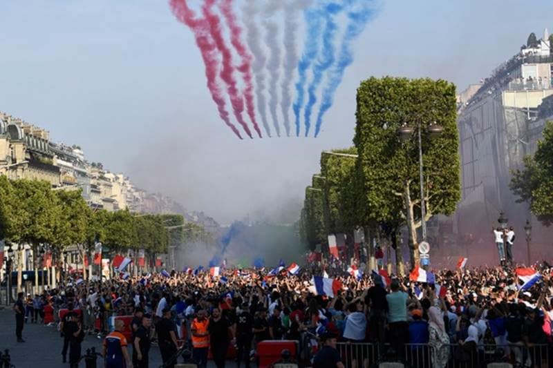 The Patrouille de France jets perform as they trail smoke in the colours of the French national flag while flying over the Champs Elysee avenue as supporters welcome players of the French national football team after they won the Fifa World Cup, in Paris.