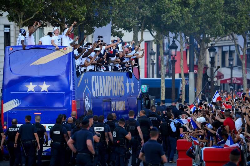 France's fans wave French national flags, light flares and cheer France's team players as they celebrate on the roof of a bus while parading down the Champs-Elysee avenue after winning the FIFA World Cup final match in Paris.