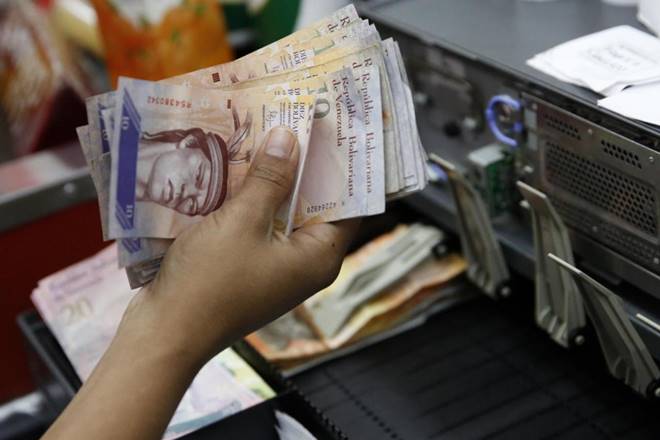 A cashier counts Venezuelan bolivar notes in a state-run supermarket in Caracas January 9, 2015. REUTERS/Carlos Garcia Rawlins