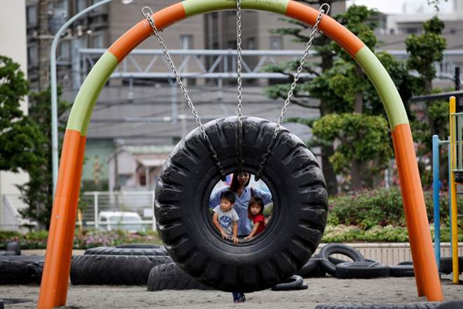 Children ride on a swing made with an old tire at Nishi Rokugo Park, also known as the Tire Park, at Ota-Ku, in Tokyo, Japan (REUTERS/Kim Kyung-Hoon/File Photo)