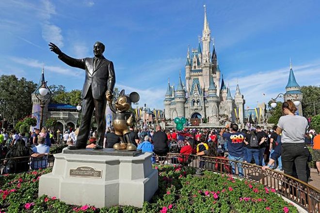 FILE - In this Jan. 9, 2019 photo, guests watch a show near a statue of Walt Disney and Micky Mouse in front of the Cinderella Castle at the Magic Kingdom at Walt Disney World in Lake Buena Vista, Fla. The Walt Disney Company reports financial results Wednesday, May 8. (AP Photo/John Raoux)

