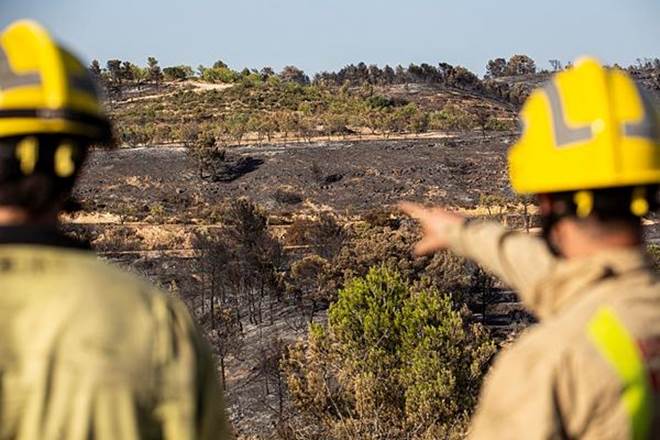 Two firefighters look at burned terrain in Spain (AP Photo)