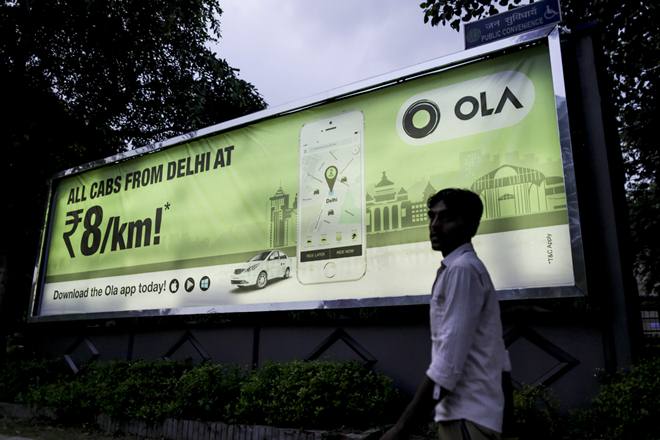 A pedestrian walks past an advertisement for the Ola ride-hailing service and application, owned by ANI Technologies Pvt., in New Delhi, India, on Saturday, Sept. 19, 2015. Ola, the operator of an Indian taxi-hailing app, will lease cars to boost the number of vehicles in its network to stave off competition from Uber Technologies Inc. Photographer: Dhiraj Singh/Bloomberg
