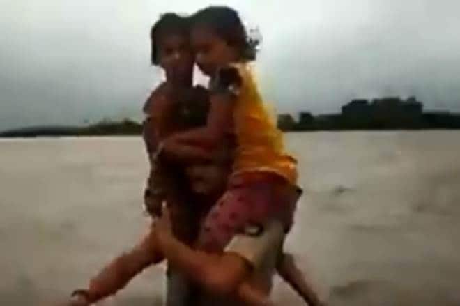 The video was shared wildly after news agency ANI has uploaded a 30-second clip of Jadega walking through the flood water with the two children on his shoulders. (ANI image)