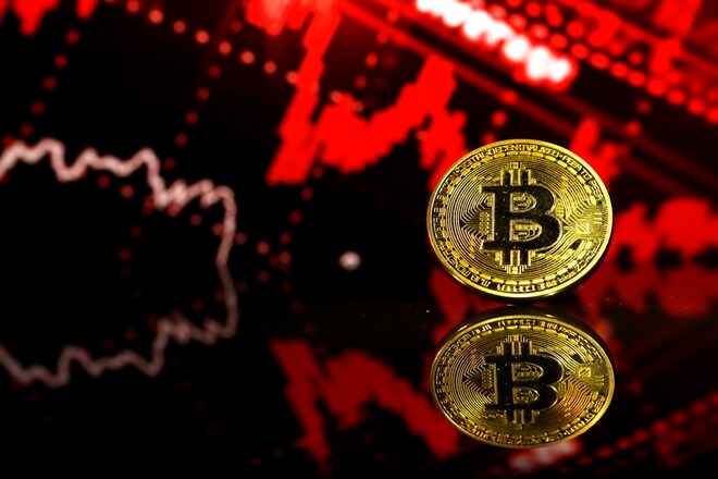 FILE: A coin representing Bitcoin cryptocurrency sits reflected on a polished surface and photographed against a photo illustration of electronic data indicating stocks falling in this arranged photograph in London, U.K., on Thursday, Feb. 8, 2018. The great cryptocurrency crash of 2018 is heading for its worst week yet. Bitcoin sank toward $4,000 and most of its peers tumbled on Friday, extending the Bloomberg Galaxy Crypto Indexs weekly decline to 25 percent. Thats the worst five-day stretch since crypto-mania peaked in early January. Photographer: Luke MacGregor/Bloomberg