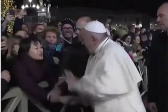 The 83-year-old pope grimaced and scowled before managing to break free, slapping her hand twice as a security guard intervened. (Source: Screengrab)