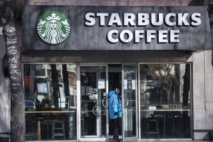 A delivery driver wearing a protective mask enters a Starbucks Corp. store in Beijing, China, on Tuesday, March 17, 2020. China suffered an even deeper slump than analysts feared at the start of the year as the coronavirus shuttered factories, shops and restaurants across the nation, underscoring the fallout now facing the global economy as the virus spreads around the world. Photographer: Qilai Shen/Bloomberg