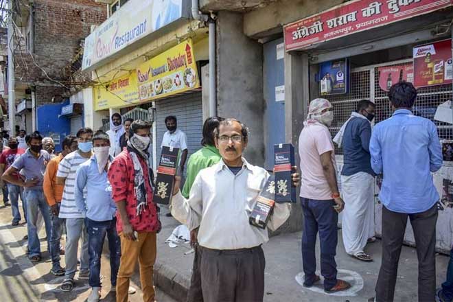 Prayagraj: People purchase alcohol from a wine shop after authorities allowed sale of liquor with certain restrictions, during the ongoing COVID-19 nationwide lockdown, in Prayagraj. (PTI Photo)