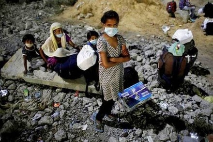 Children of migrant workers wearing protective face masks wait to cross the border to their home state of Uttar Pradesh, during an extended nationwide lockdown to slow the spread of the coronavirus disease (COVID-19), in New Delhi. (Courtesy: Reuters photo)