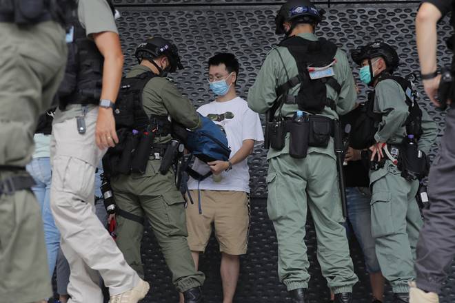 Riot police checks a man near the U.S. Consulate in Hong Kong, Saturday, July 4, 2020 to mark the American Independence Day or "the Fourth of July." China's government and pro-Beijing activists in Hong Kong are condemning what they call foreign meddling in the territory's affairs, as countries move to offer Hong Kongers refuge and impose sanctions on China over a new security law. (AP Photo/Kin Cheung)