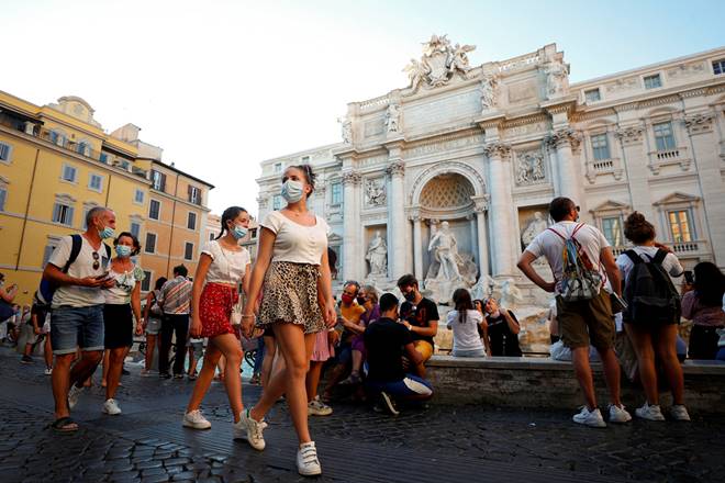 FILE PHOTO: People wearing face masks walk in front of the Trevi Fountain following a government decree that states face coverings must be worn between 6 p.m. and 6 a.m. near bars and pubs and in areas where gatherings are more likely, due to the coronavirus disease (COVID-19) outbreak, in Rome, Italy August 19, 2020. REUTERS/Guglielmo Mangiapane/File Photo FILE PHOTO: People wearing face masks walk in front of the Trevi Fountain following a government decree that states face coverings must be worn between 6 p.m. and 6 a.m. near bars and pubs and in areas where gatherings are more likely, due to the coronavirus disease (COVID-19) outbreak, in Rome, Italy August 19, 2020. REUTERS/Guglielmo Mangiapane/File Photo