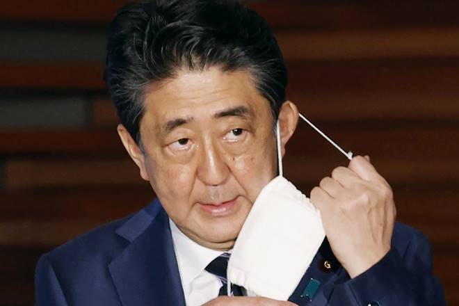 FILE - In this May 21, 2020, file photo, Japan's Prime Minister Shinzo Abe removes a face mask as he speaks at a press conference in Tokyo. Prime Minister Abe on Monday became Japan's longest-serving leader in terms of consecutive days in office, but there was little fanfare, as he visited a hospital for another health checkup amid concerns about his health. (Kyodo News via AP, File)