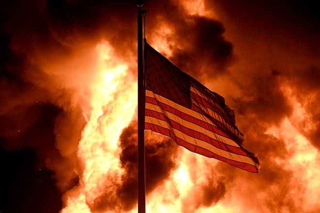 Flames engulf the Community Corrections Division building as an American flag flutters on a pole as protests turn to fires after a Black man, identified as Jacob Blake, was shot several times by police last night in Kenosha, Wisconsin, U.S. August 24, 2020. Picture taken August 24, 2020. REUTERS/Stephen Maturen TPX IMAGES OF THE DAY