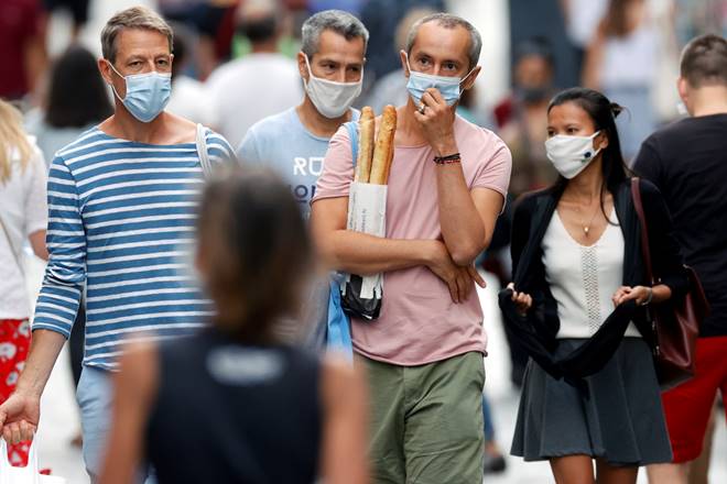 FILE PHOTO: People wearing protective masks walk in the Montorgueil street as France reinforces mask-wearing as part of efforts to curb a resurgence of the coronavirus disease (COVID-19) across the country, in Paris, France, August 22, 2020. REUTERS/Christian Hartmann/File Photo