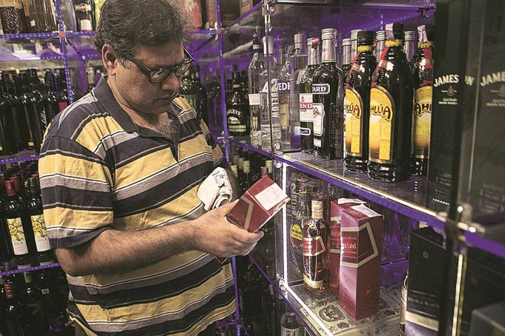 A customer looks at a bottle of Diageo Plc's Red Label whiskey at a liquor store in New Delhi, India, on Monday, Nov. 12, 2012. United Spirits Ltd. surged by a record in Mumbai trading after Diageo Plc said it will buy a controlling stake in India’s largest distiller for $2.04 billion. Photographer: Prashanth Vishwanathan/Bloomberg