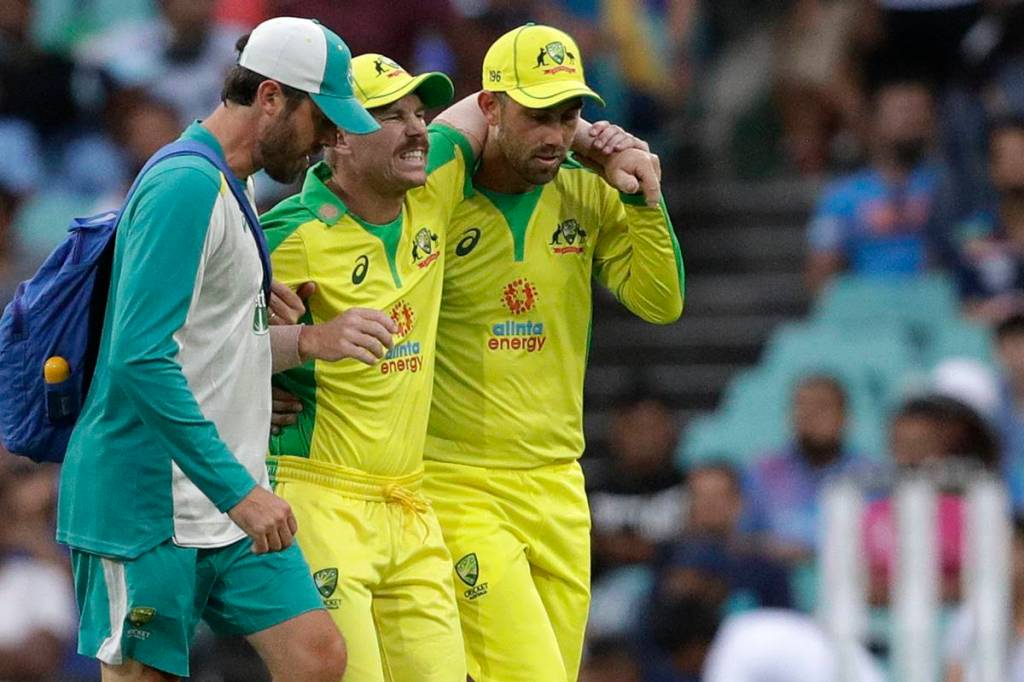 Australia's David Warner, centre, is assisted from the field after injuring himself while fielding during the one day international cricket match between India and Australia at the Sydney Cricket Ground in Sydney, Australia. (AP Photo)