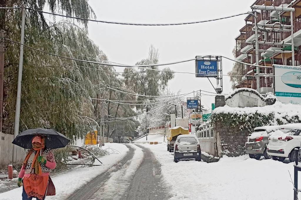A woman, carrying an umbrella, walks during snowfall in Manali. (PTI Photo)