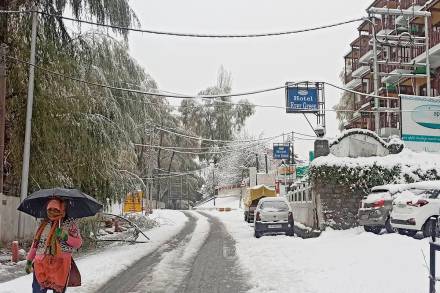 A woman, carrying an umbrella, walks during snowfall in Manali. (PTI Photo)
