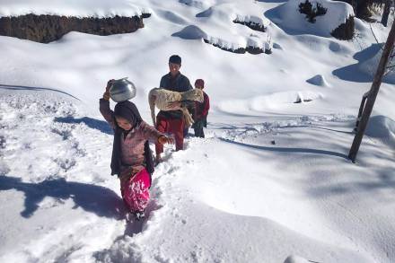 Children carrying water pitchers and goat walk on a snow covered area after the town received fresh snowfall, at Bhaderwah in Doda district. (PTI Photo)